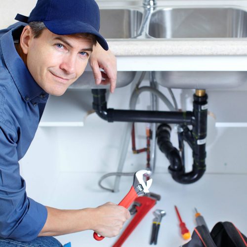 man smiling while holding wrench